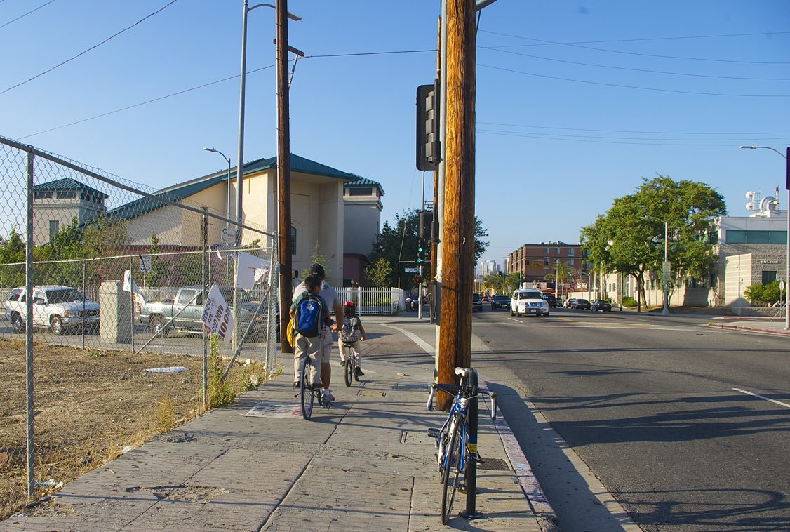 A father runs errands with his children along Central Avenue after picking them up from school. Sahra Sulaiman/Streetsblog L.A.