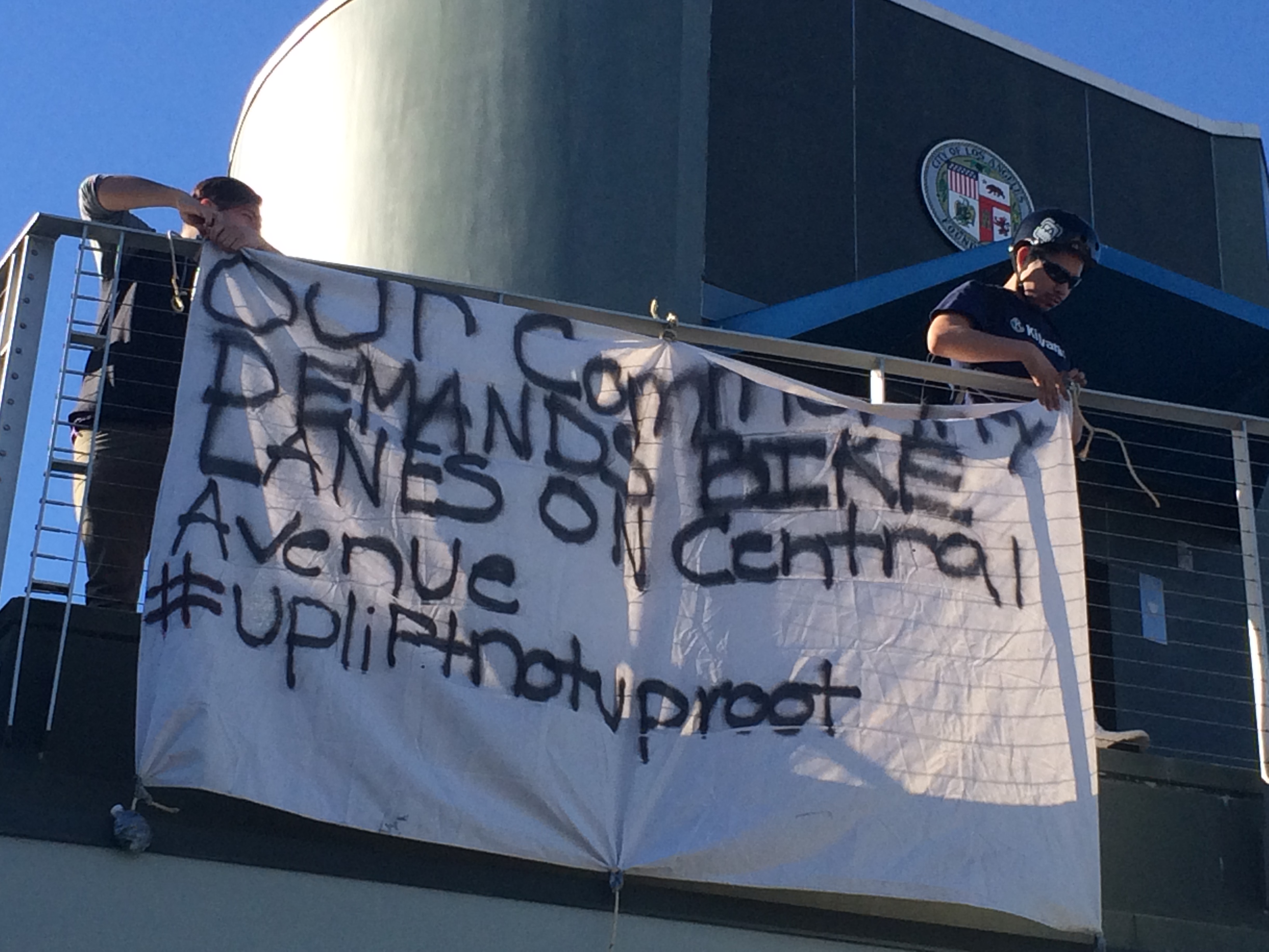 Members of TRUST South L.A. hang a banner from Curren Price's constituent center. Photo: Ashley Hansack