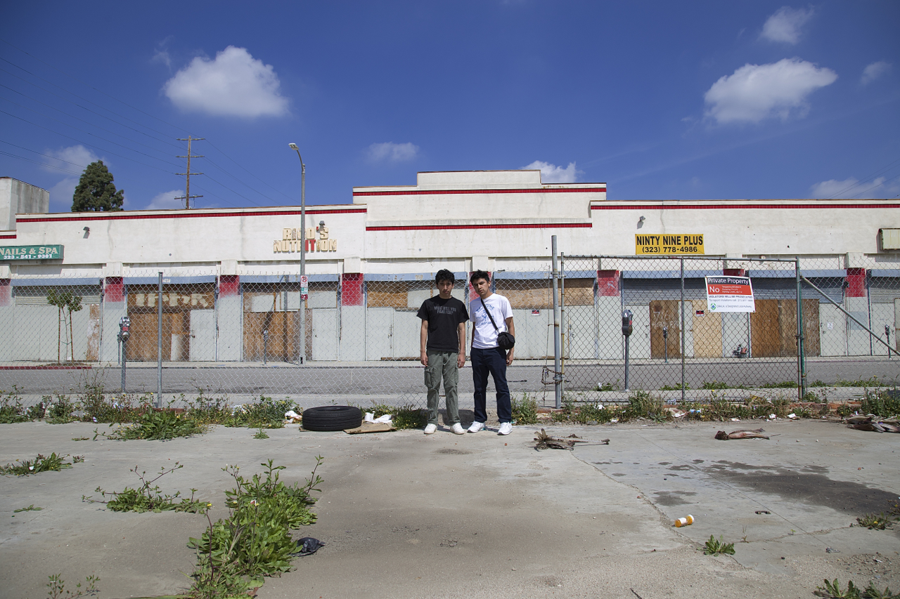 Juan Carlos Mercado and Miguel Sanchez stand in a vacant lot at Manchester and Vermont. The former swap meet site saw a groundbreaking two years ago but the mall project, planned by developer Eli Sasson, has yet to materialize. Sahra Sulaiman/Streetsblog L.A.