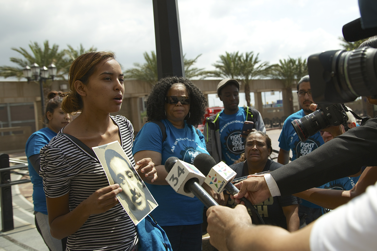 Evelia Granados holds a photo of her brother, Cesar Rodriguez, who was killed by a train while interacting with the Long Beach Police regarding fare evasion. Rodriguez' mother, Rosa Moreno (seated, in the black shirt), looks on as her daughter speaks. Sahra Sulaiman/Streetsblog L.A.