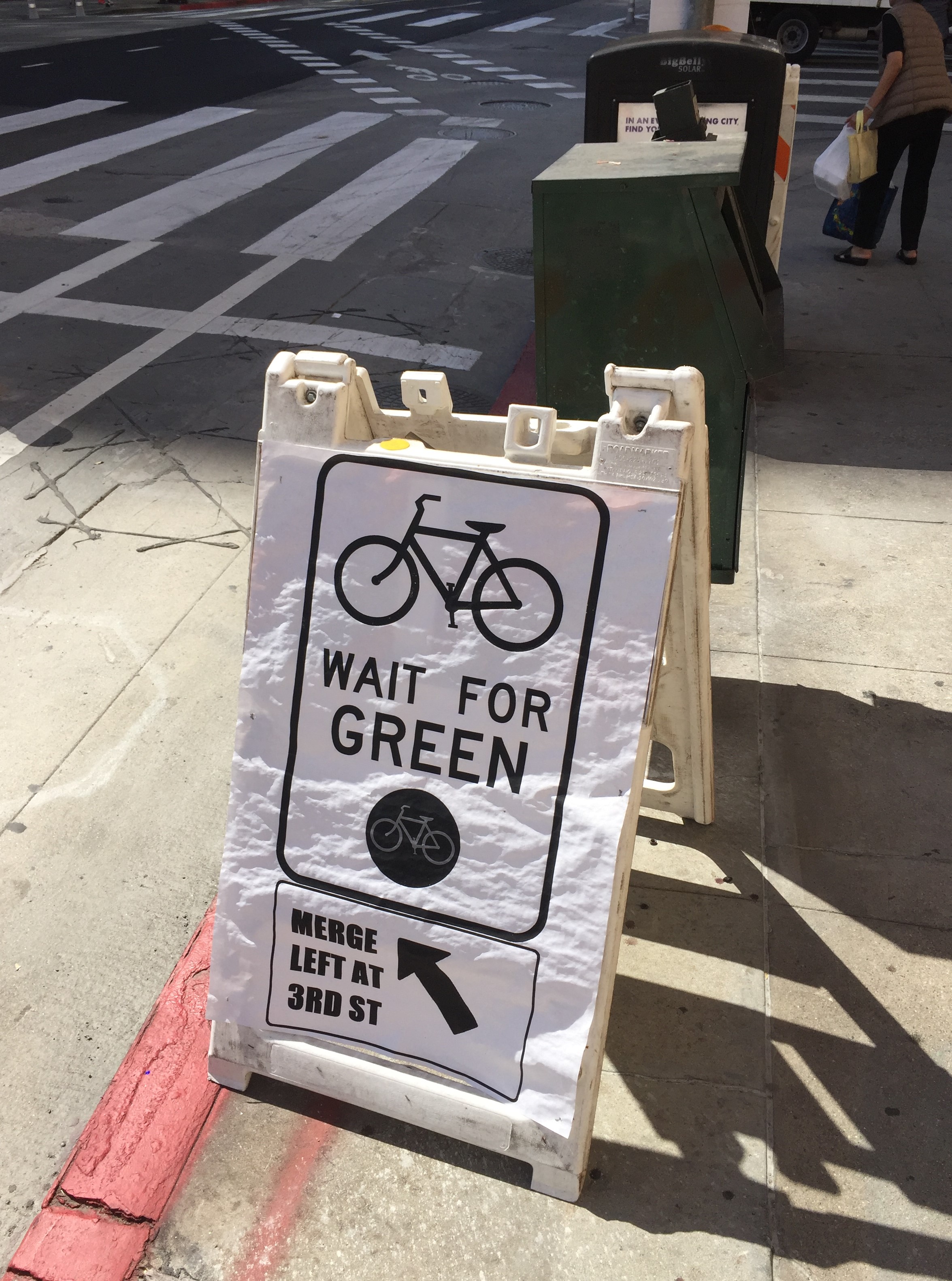Temporary signage alerts cyclists to cross to the left side of the street at 3rd Street