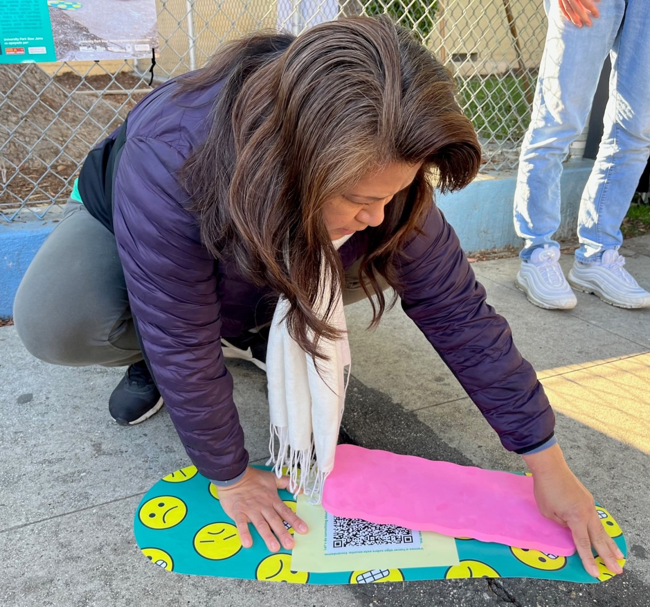 Volunteer placing a sticker on the sidewalk along South L.A.'s Oak Street